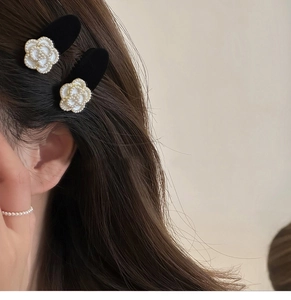 Detail of camellia hair clips with white pearls and black velvet on a female model