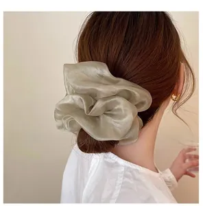 Detailed view of oversized champagne organza scrunchie with soft pleated texture