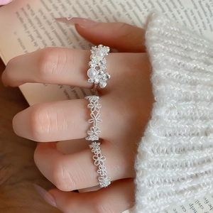 Detailed view of silver flower rings set with pearls on finger for an elegant style