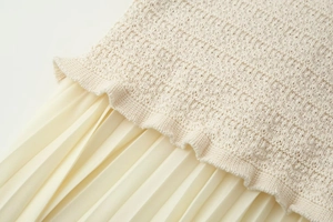 Détail de la texture en maille et de l'ourlet plissé d'un ensemble en tricot crème