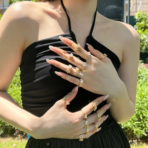 Close-up of gold adjustable letter and heart rings with zircons worn as a set