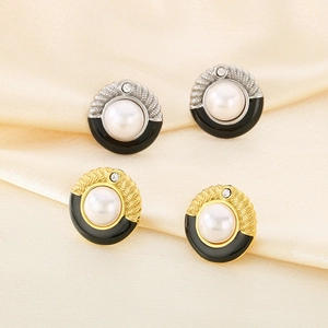 Detail of pearl and black enamel earrings in gold and silver finish on silk background