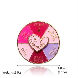 Close-up of a 4.0cm rotating enamel mood badge with motivational phrases and pink gradient