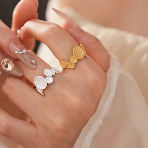 Detailed view of matte gold and white oval textured open ring worn on a finger