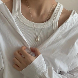 Close-up of a large white pearl pendant with silver mounting on a delicate bead chain