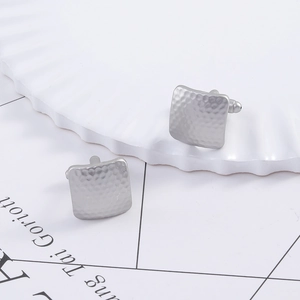 Detail of square silver cufflinks with hammer-textured surface for business wear