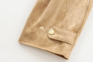 Macro detail of camel faux suede jacket sleeve with gold metal snap buttons and tabs