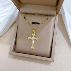 Macro view of gold cross pendant with clear pavé zircon stones on champagne leather