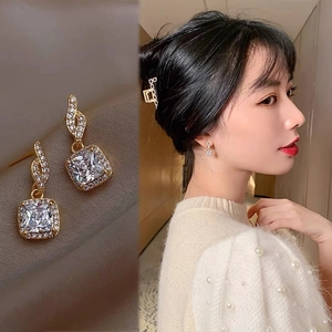 Detail of square-cut clear crystal drop earrings with pavé rhinestones in gold finish