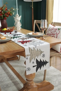 Detail of Christmas table runner featuring festive tree patterns on a wooden table
