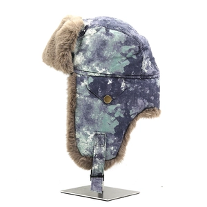 Detail view of winter camouflage trapper hat with thick brown faux fur lining and buckle