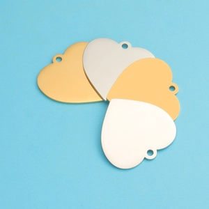 Polished gold and silver heart-shaped stainless steel pendants on a blue surface