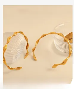 Detailed macro view of gold-plated wavy geometric bangles with mirror finish