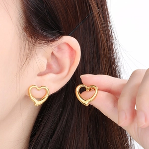 Gros plan de boucles d'oreilles cœur doré portées par un mannequin montrant les détails