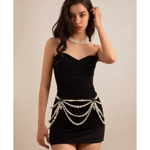 Detailed view of layered white pearl body chain and necklace on a black dress