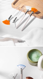 Detail of fan-shaped facial mask brushes with colorful bristles and clear handles