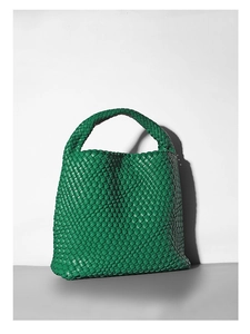 Close-up of a green hand-woven bucket bag with a premium leather textured handle