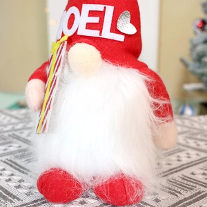 Macro detail of plush Christmas gnome with Noel lettering and soft glowing festive background