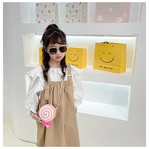 Girl wearing a pink lollipop crossbody bag with ribbon and spiral pattern detail
