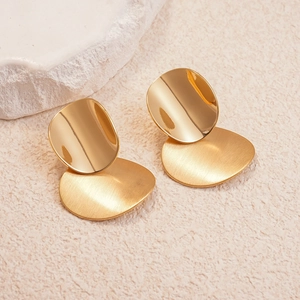 Detail view of gold geometric oval earrings with brushed matte texture and smooth metal