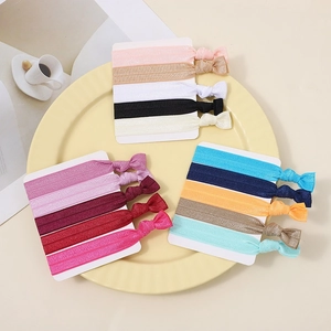 Set of 15 colorful knotted elastic hair bands in pink and beige on a yellow display tray