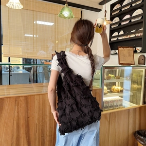 Detail view of the black canvas tote bag featuring layered tassel fringe texture and large capacity
