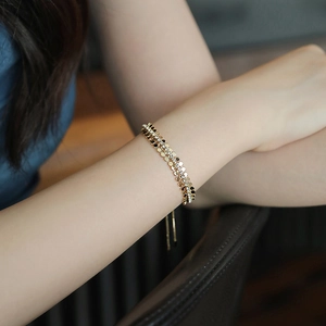Bracciale multistrato vintage dorato con zirconi e paillettes sul polso di una modella