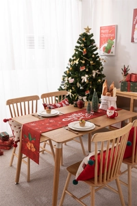 Detailed view of Merry Christmas text and festive bell patterns on a red table runner