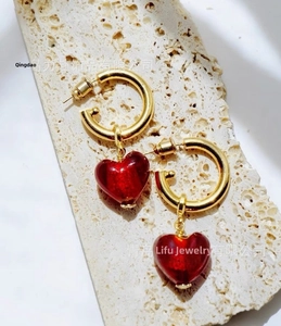 Close-up of gold plated hoop earrings with red Murano glass heart shaped pendants