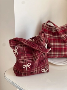 Detailed texture of red plaid wool bag featuring white embroidered bow tie patterns