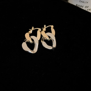 Détail de boucles d'oreilles chaînes entrelacées bicolores sur fond en velours noir