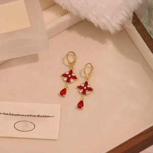 Vintage gold floral drop earrings with red gemstones and crystals on beige tray