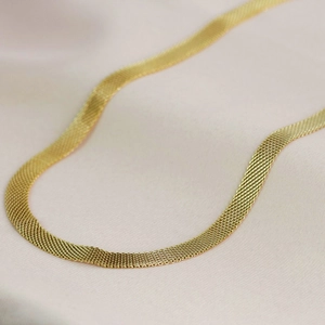 Close-up of gold wide hollow mesh chain necklace with woven metallic texture