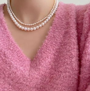 Close-up of double-layer 925 silver necklace with 10mm white pearls on pink sweater
