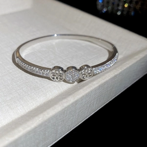 Detailed macro of silver plated bangle with pave zircons and hollow floral motif