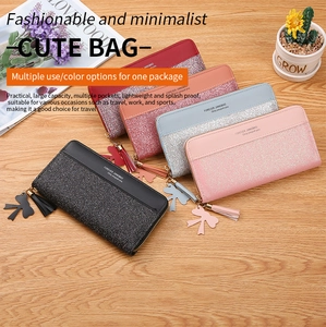 Group of sequin long zip wallets in five colors with bow tassels on wooden desk