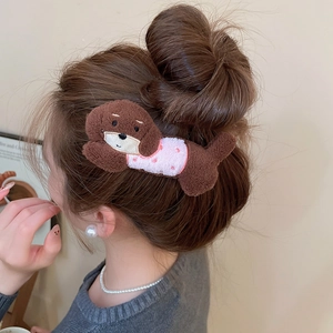 Close-up of a plush brown puppy hair clip with pink polka dot dress on a model