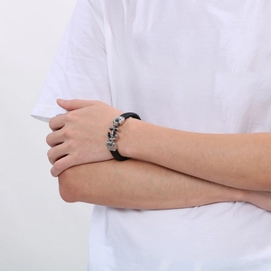 Détail d'un bracelet en cuir tressé noir avec breloque ancre argentée sur le poignet d'un homme