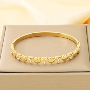 Detailed view of gold heart bracelet with pavé cubic zirconia on satin background
