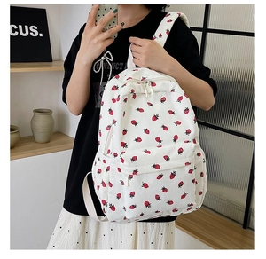 Detailed side view of corduroy backpack featuring strawberry print and front pocket