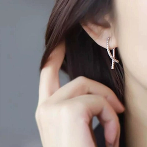 Detail of silver crisscross hoop earrings with small diamonds on a female model