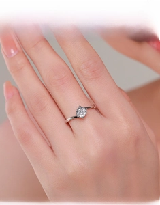 Close-up of a s925 silver four-prong classic engagement ring worn on a finger