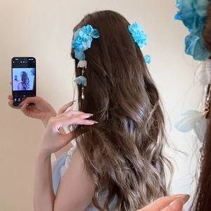 Détail d'une pince à cheveux fleur en soie bleue avec deélégants glands de perles longs