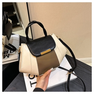 Close-up of color-block PU leather handbag with gold hardware and embossed fashion logo