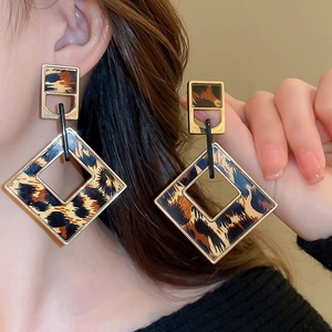 Macro shot of geometric resin leopard print earrings with elegant gold metal framing