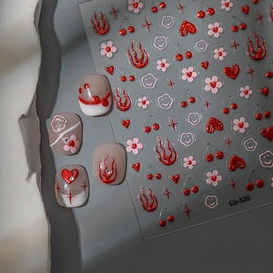 Macro shot of 3D embossed nail art stickers with metallic red hearts and flame patterns
