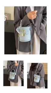 Detail of light blue quilted barrel bag with gold hardware and decorative floral silk scarf