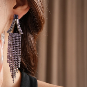 Detail shot of long purple crystal tassel earrings with geometric rhinestone studs on model
