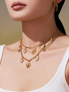 Détail d'un collier doré à pendentifs cœur et de boucles d'oreilles porté par un mannequin