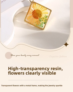 Close-up of square clear resin pendant with yellow dried flowers and gold metal twist border